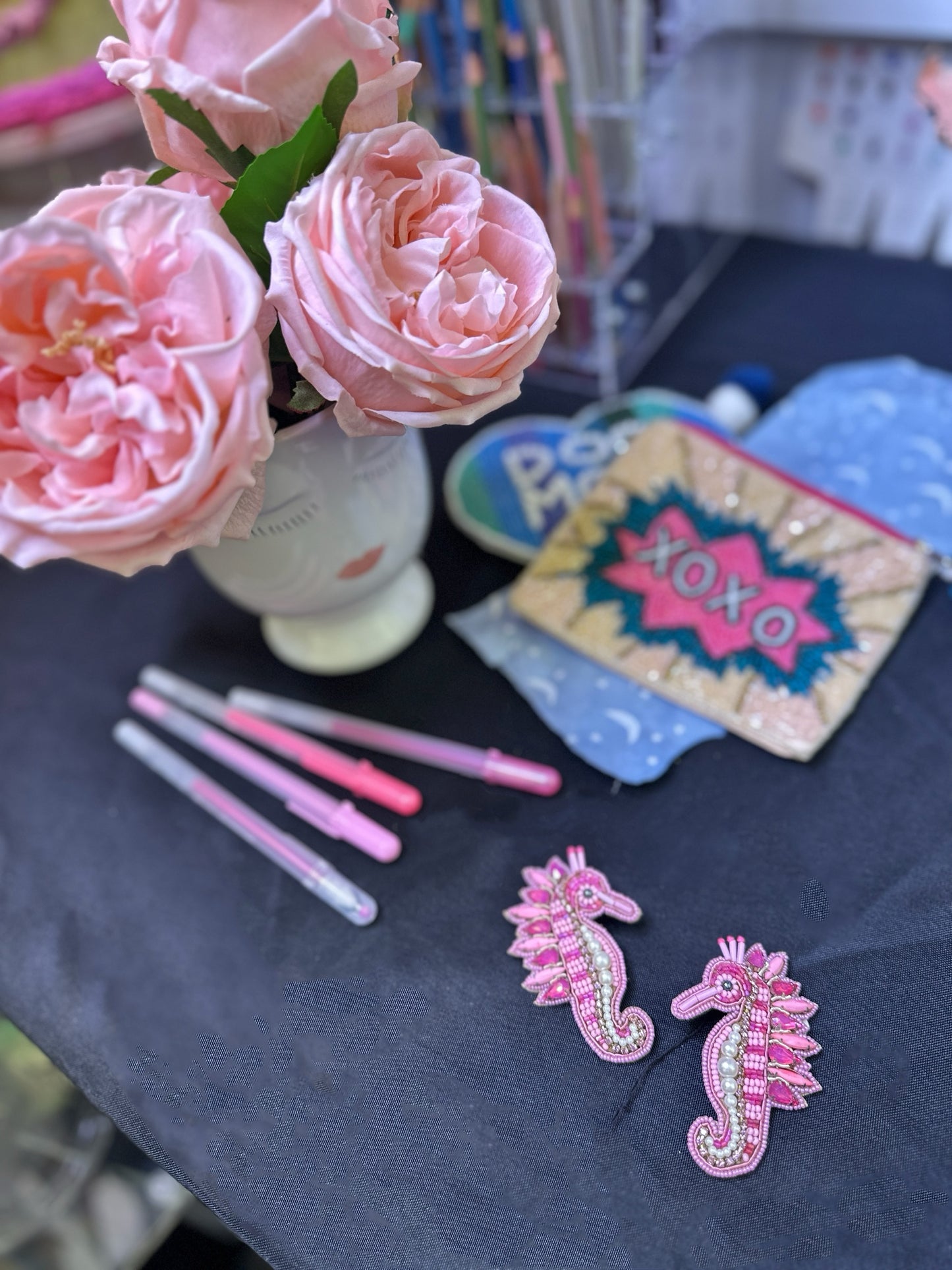 Rosy Seahorse earrings styled against a vibrant background with layered textures and patterns, highlighting their playful and whimsical design.