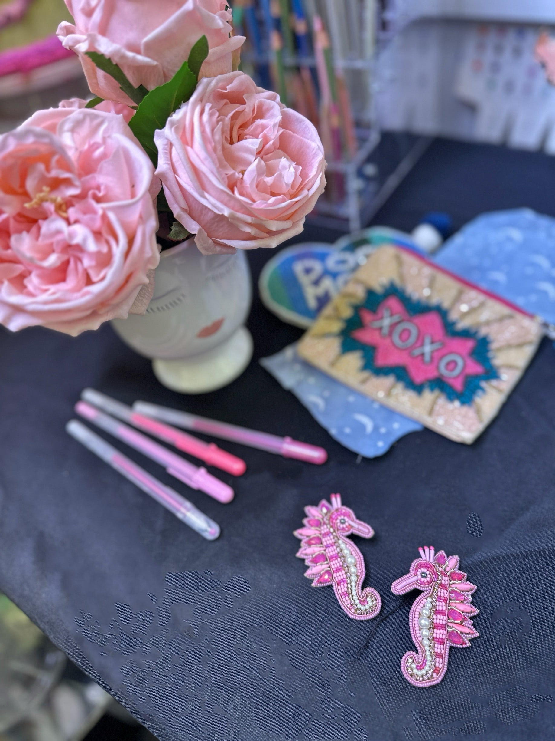 Rosy Seahorse earrings styled against a vibrant background with layered textures and patterns, highlighting their playful and whimsical design.
