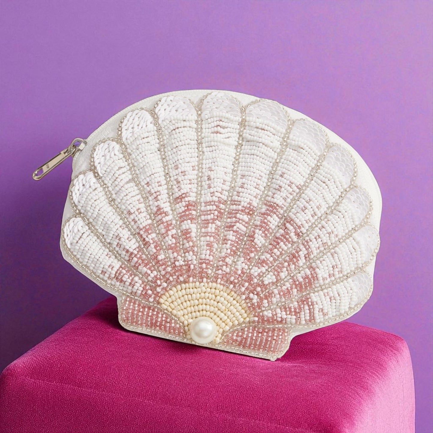 Beaded shell pouch in white and pink ombré displayed upright on a magenta block against a purple background.