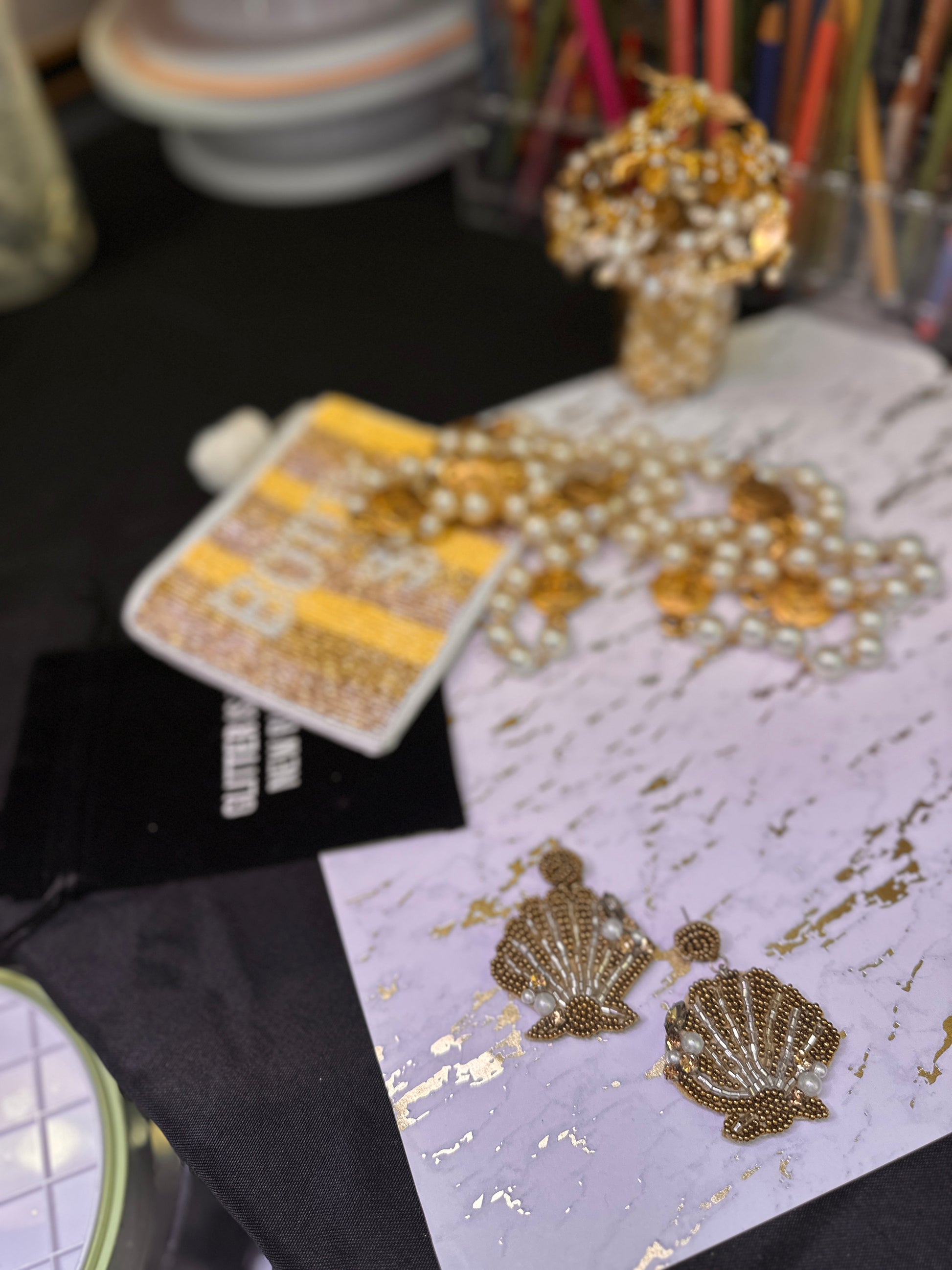Gold and pearl shell-shaped statement earrings displayed on a marble and gold background with coordinating accessories in the scene, styled for an elegant beachy vibe.