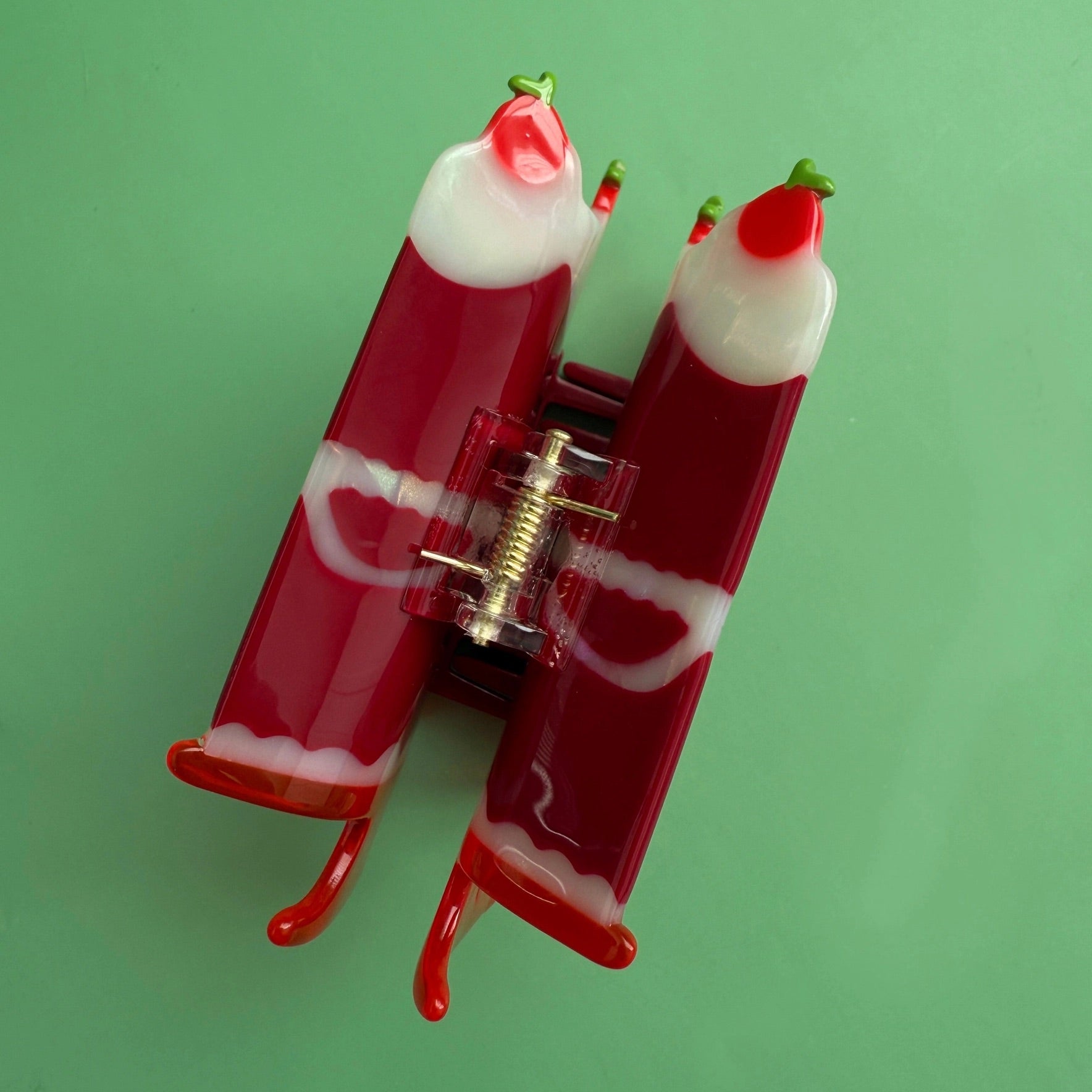 Red cake-shaped claw hair clip with clear hinge, viewed from the side