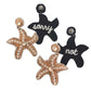 Stylish starfish earrings with beaded design and "Not Sorry" patch, perfect for an ocean-inspired look.
