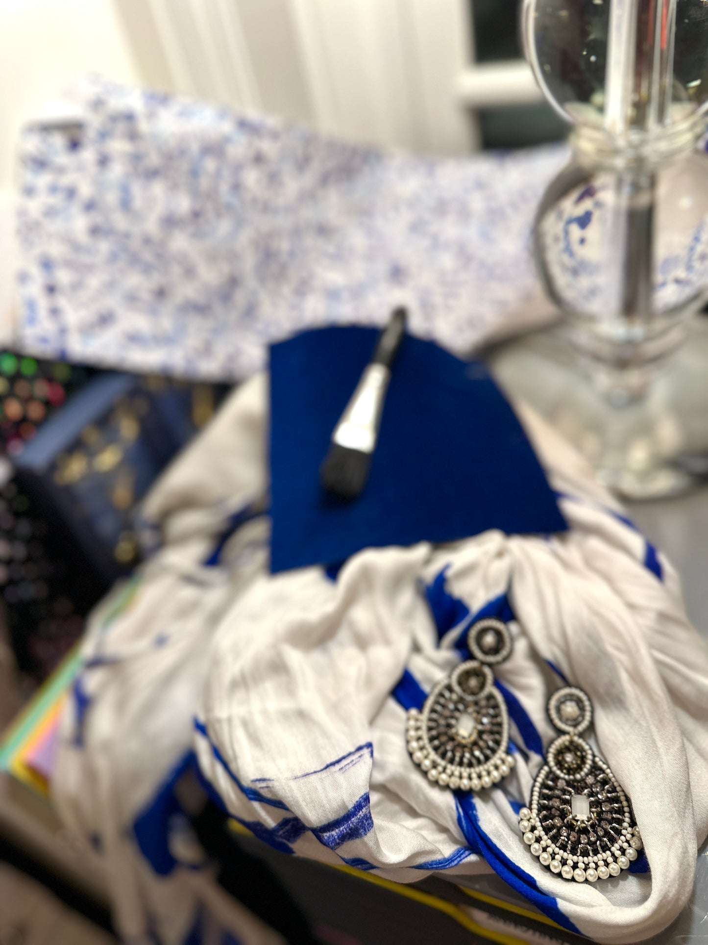 Terra cotta drop earrings with beaded detailing styled beside a vintage book set and amber candle jar on a neutral stone background.