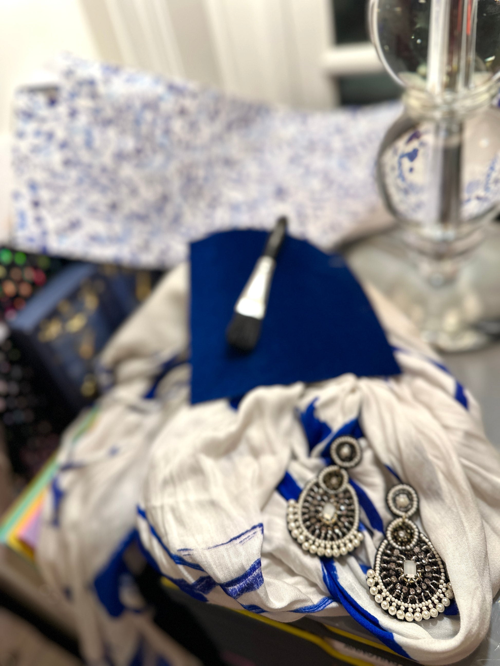 Terra cotta drop earrings with beaded detailing styled beside a vintage book set and amber candle jar on a neutral stone background.