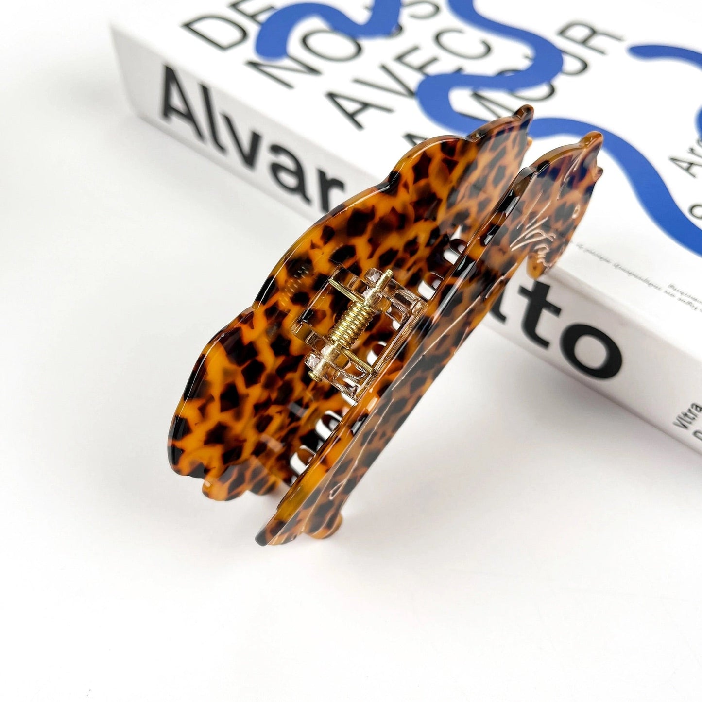 Claw clip shaped like a seated leopard in tortoise pattern, styled with books.